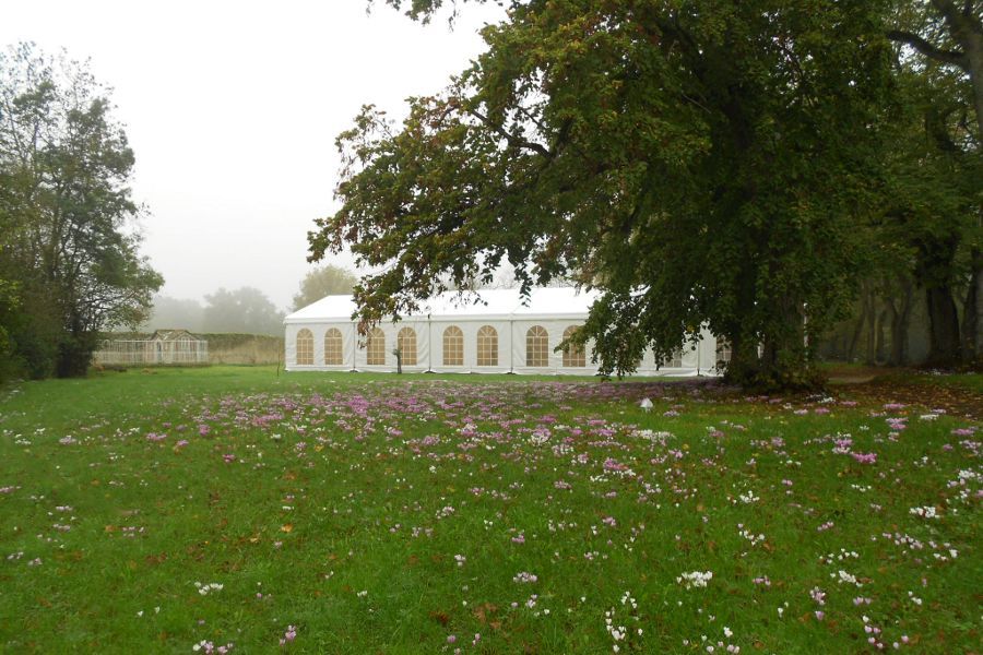 Réception de mariage organisé sous des tentes installées dans un jardin fleuri